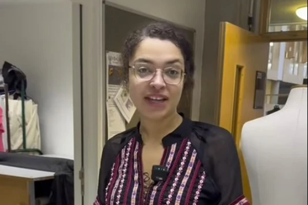 HNC costume design student presenting their work in a classroom, with sewing patterns and fabric samples on the table. HNC costume design student presenting their work in a classroom, with sewing patterns and fabric samples on the table.