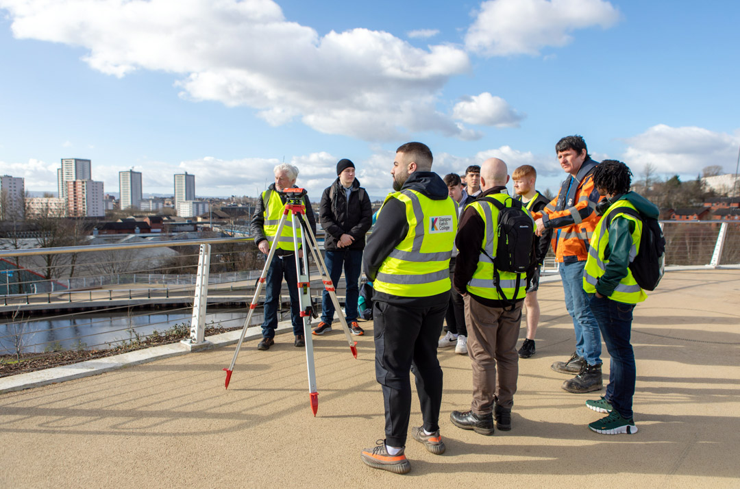 Civil engineering students using surveying equipment during an outdoor fieldwork session overlooking Glasgow.