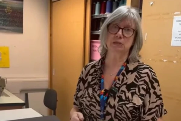 Fashion lecturer explaining costume design techniques, showcasing a sketchbook with fabric embellishment samples in a classroom. Fashion lecturer explaining costume design techniques, showcasing a sketchbook with fabric embellishment samples in a classroom.