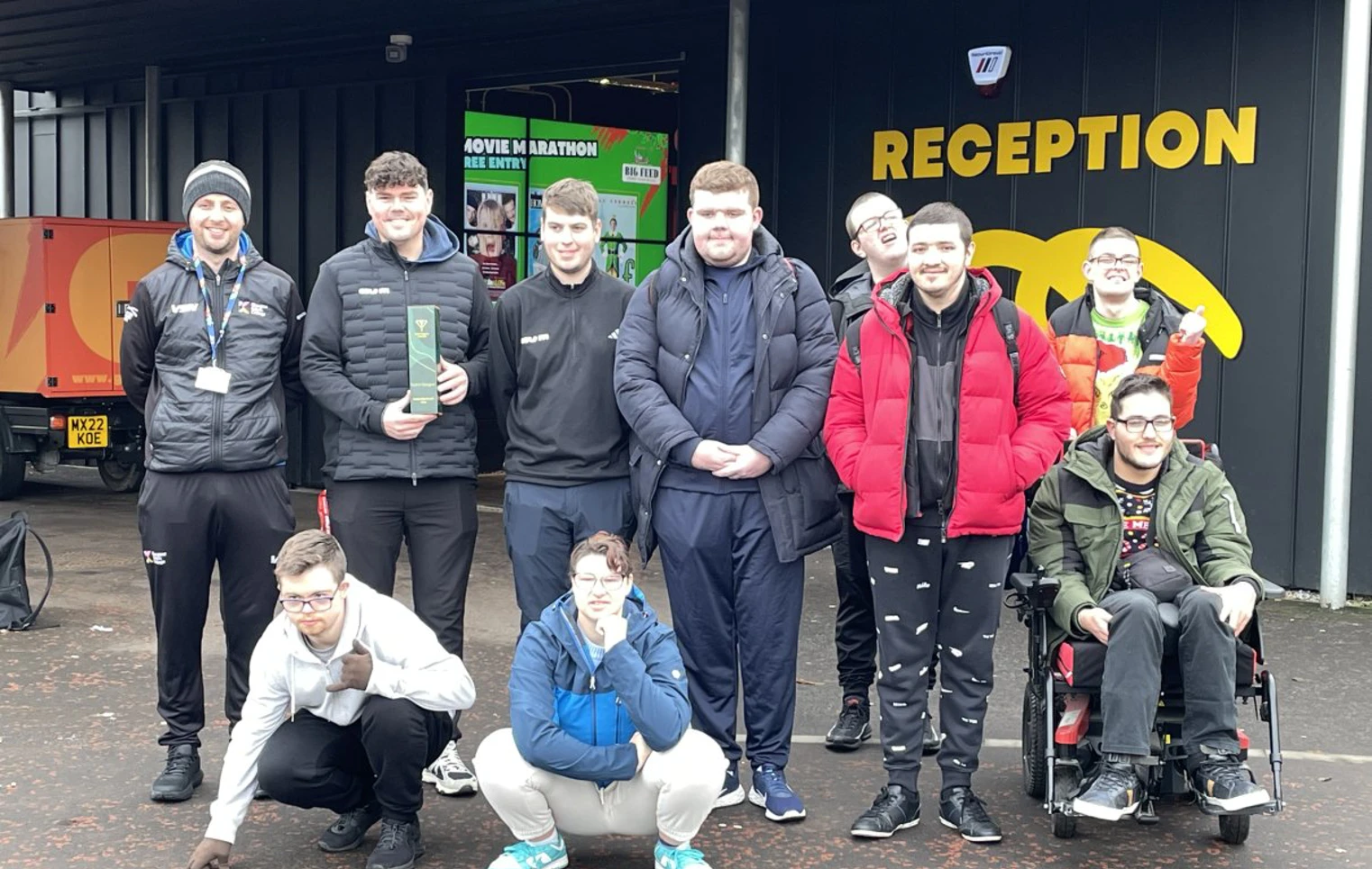 Group of Glasgow Kelvin College students and staff smiling outside the Golf It! reception, some crouching and one in a wheelchair, after a visit. Group of Glasgow Kelvin College students and staff smiling outside the Golf It! reception, some crouching and one in a wheelchair, after a visit.