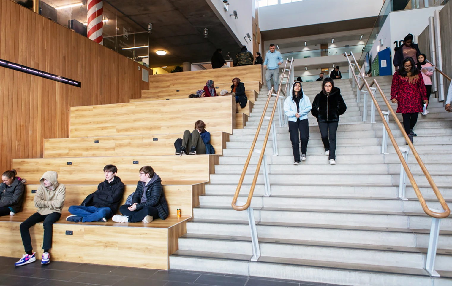 Students sitting and walking on the main staircase and tiered wooden seating area at Glasgow Kelvin College’s Springburn Campus. Students sitting and walking on the main staircase and tiered wooden seating area at Glasgow Kelvin College’s Springburn Campus.