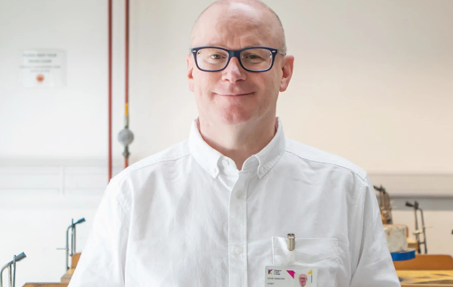 Lecturer David Webster stands in a jewellery workshop at Glasgow Kelvin College, smiling and holding a jeweller’s saw, with tools and benches in the background. Lecturer David Webster stands in a jewellery workshop at Glasgow Kelvin College, smiling and holding a jeweller’s saw, with tools and benches in the background.