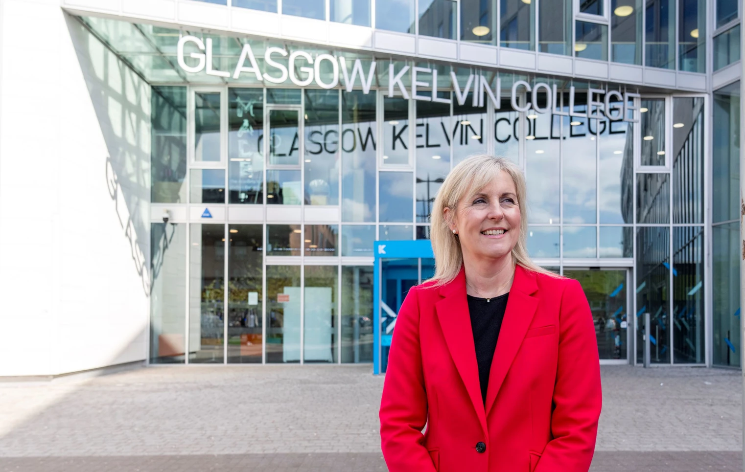 Joanna Campbell, Principal of Glasgow Kelvin College, smiling outside the college’s main entrance in a bright red blazer Joanna Campbell, Principal of Glasgow Kelvin College, smiling outside the college’s main entrance in a bright red blazer