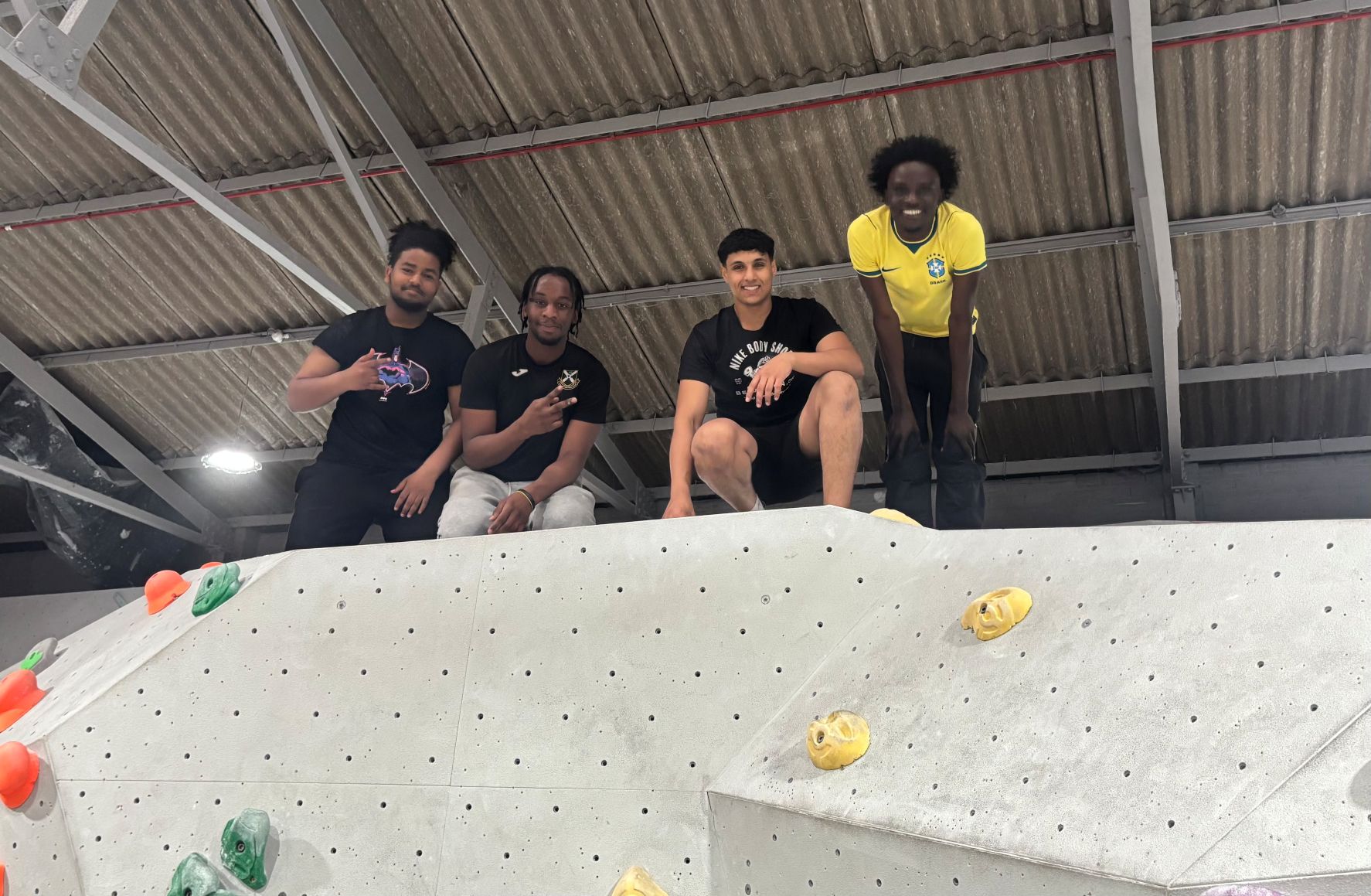 ESOL students standing on top of an indoor climbing wall during a group visit.