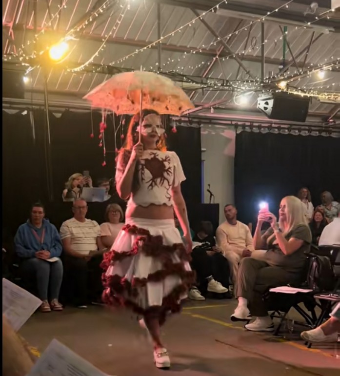 Model wearing a theatrical white and red costume while walking the runway during Glasgow Kelvin College’s Fashion Show 2026 event.