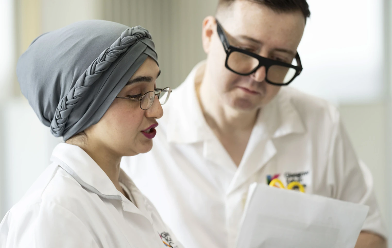 Close-up of two healthcare students reviewing patient notes in a practical classroom setting. Close-up of two healthcare students reviewing patient notes in a practical classroom setting.