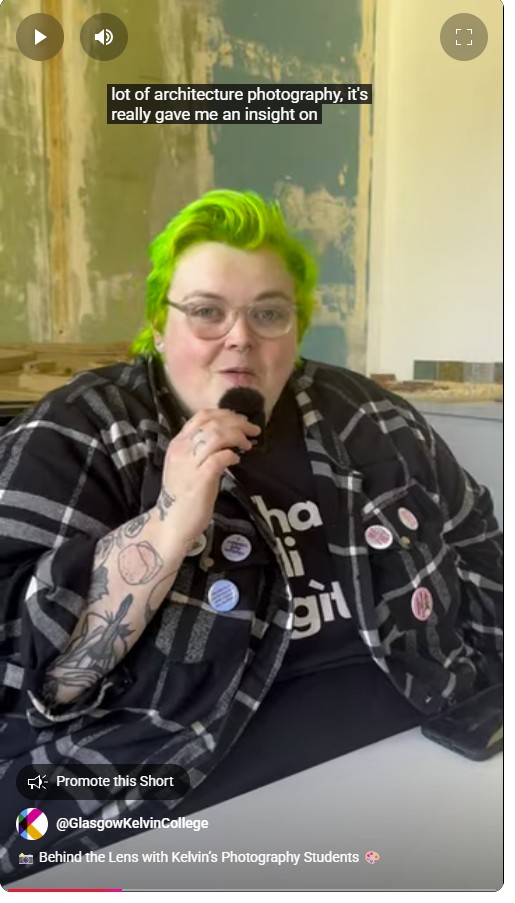 A Photography student at Glasgow Kelvin College with bright green hair and tattoos speaks into a microphone, discussing architecture photography during an interview.