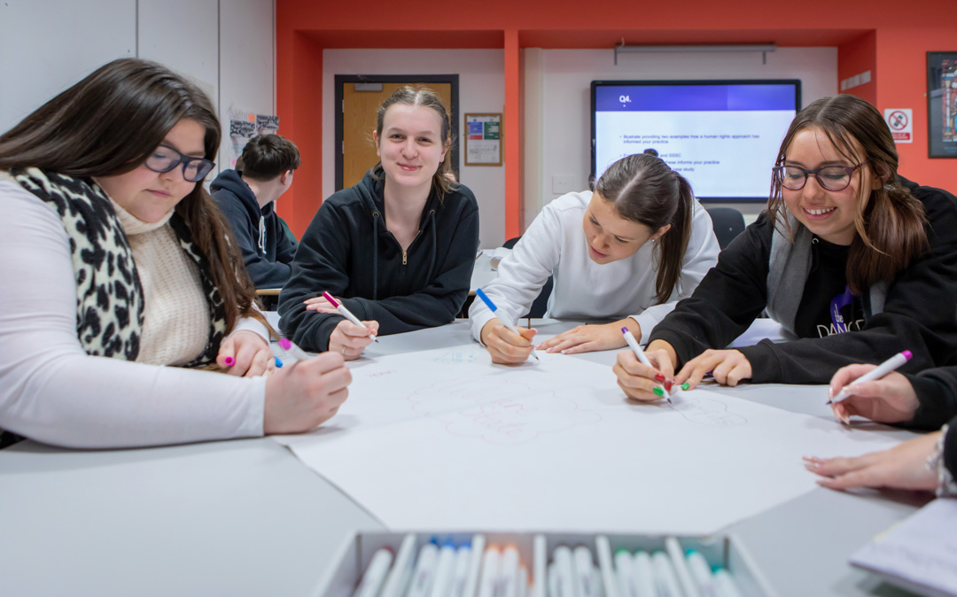 A vibrant snapshot of Glasgow Kelvin College students working together, sharing thoughts and smiles in a supportive classroom setting.
