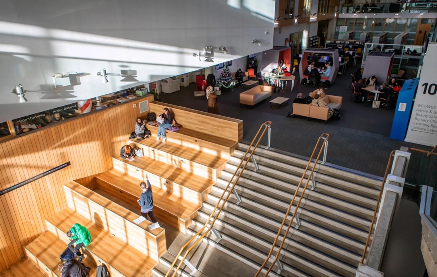 Students sitting and studying in a bright, open-plan learning space at Glasgow Kelvin College Springburn Campus, featuring tiered wooden seating and main stairway. Students sitting and studying in a bright, open-plan learning space at Glasgow Kelvin College Springburn Campus, featuring tiered wooden seating and main stairway.