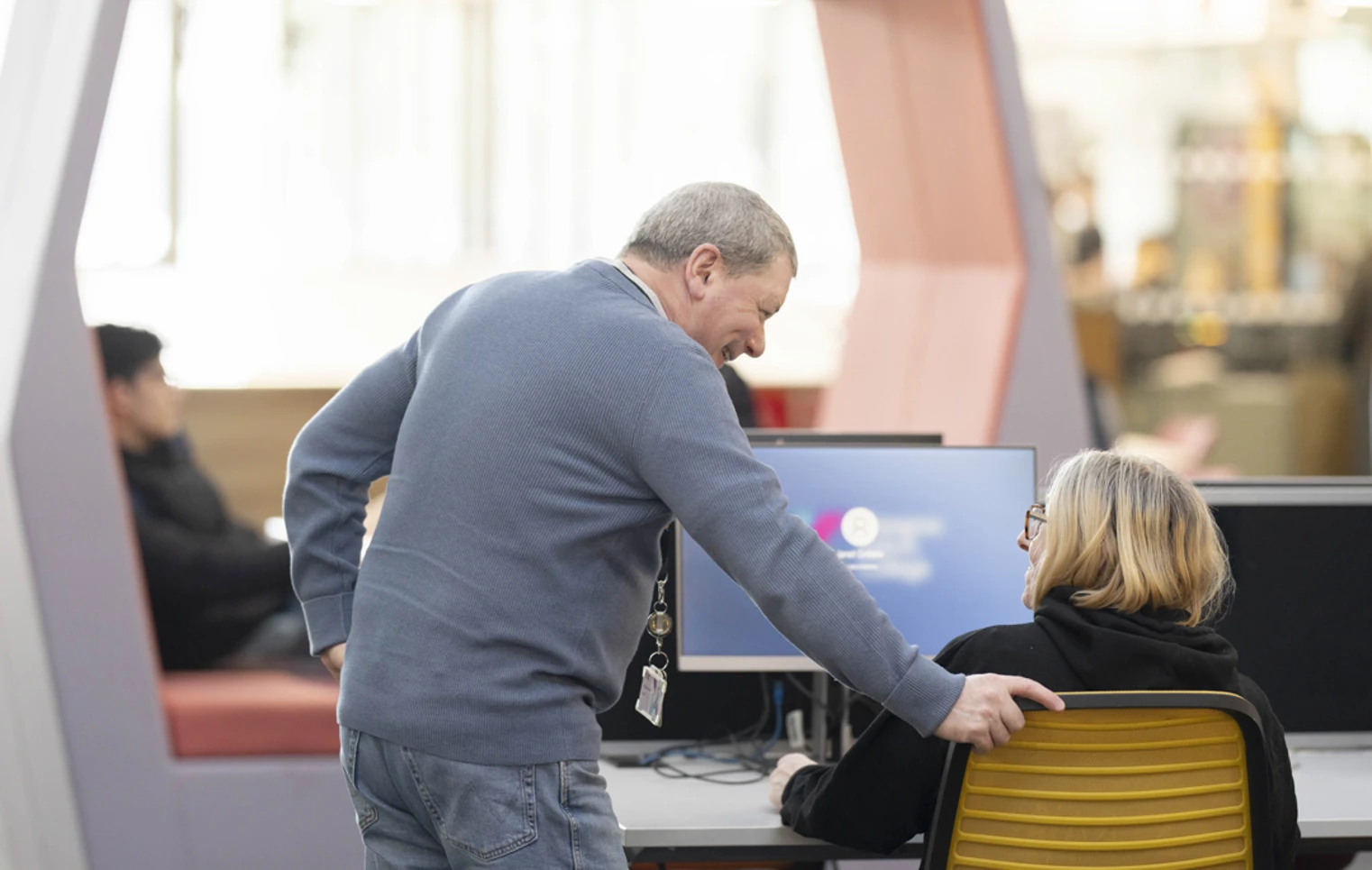 Staff member at Glasgow Kelvin College offering friendly support to a student seated at a computer in the library or learning centre. Staff member at Glasgow Kelvin College offering friendly support to a student seated at a computer in the library or learning centre.