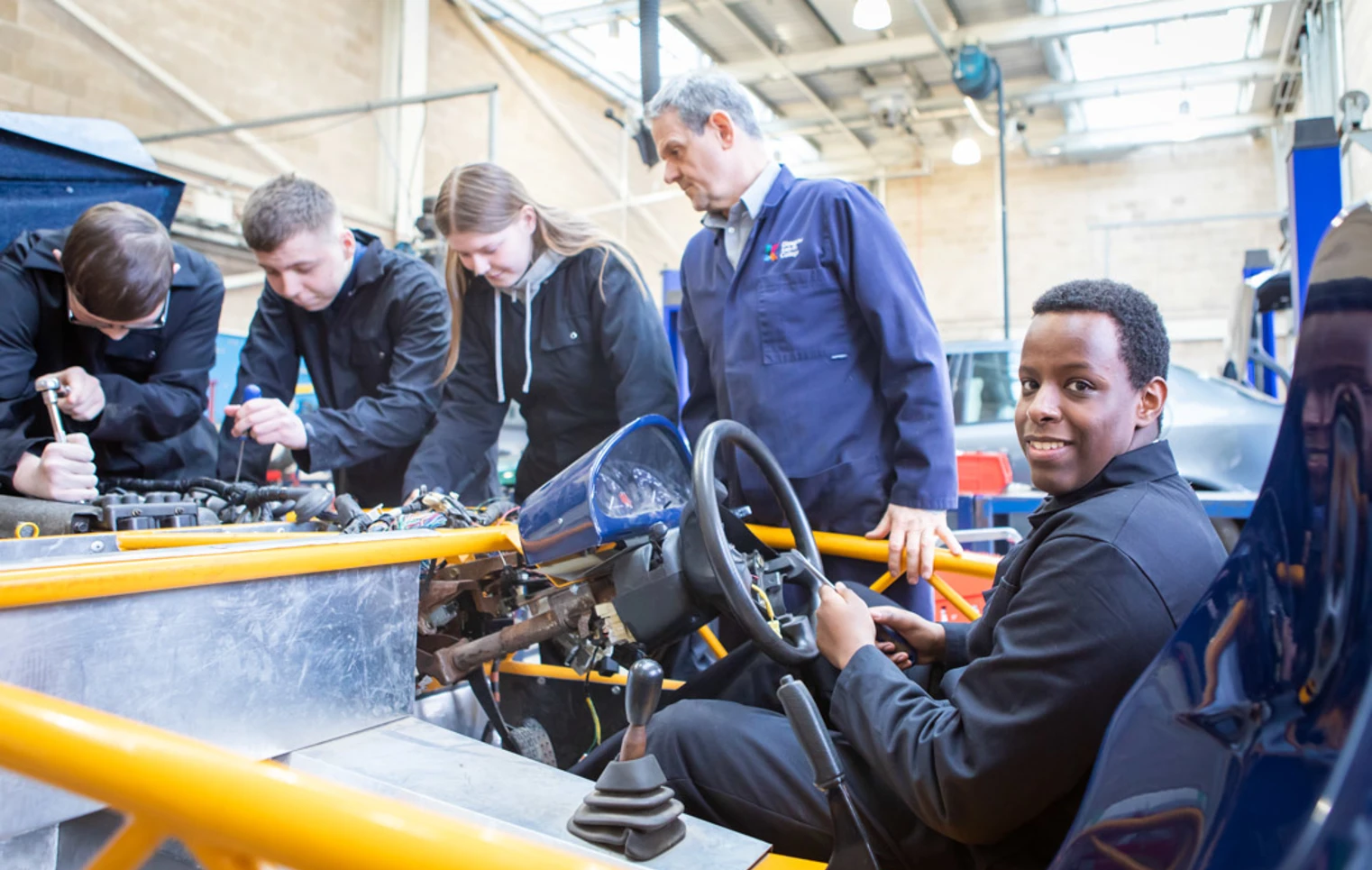 Instructor and students collaborating on an engine repair project, focusing on mechanical details in a hands-on learning session. Instructor and students collaborating on an engine repair project, focusing on mechanical details in a hands-on learning session.