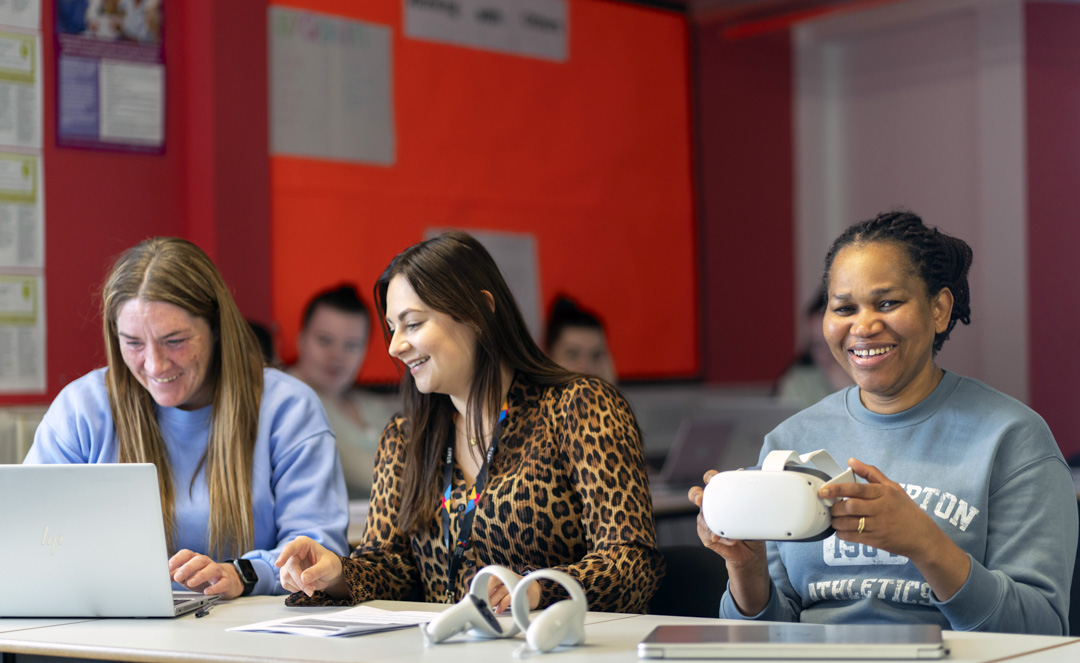 Students and staff seated at tables with laptops and virtual reality equipment during a learning session at Glasgow Kelvin College.