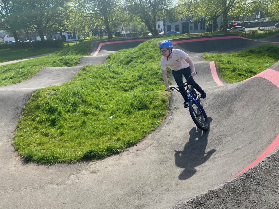 Student riding a BMX bike on an outdoor pump track during a sunny day, part of the Pathways to Employment Skills programme. Student riding a BMX bike on an outdoor pump track during a sunny day, part of the Pathways to Employment Skills programme.