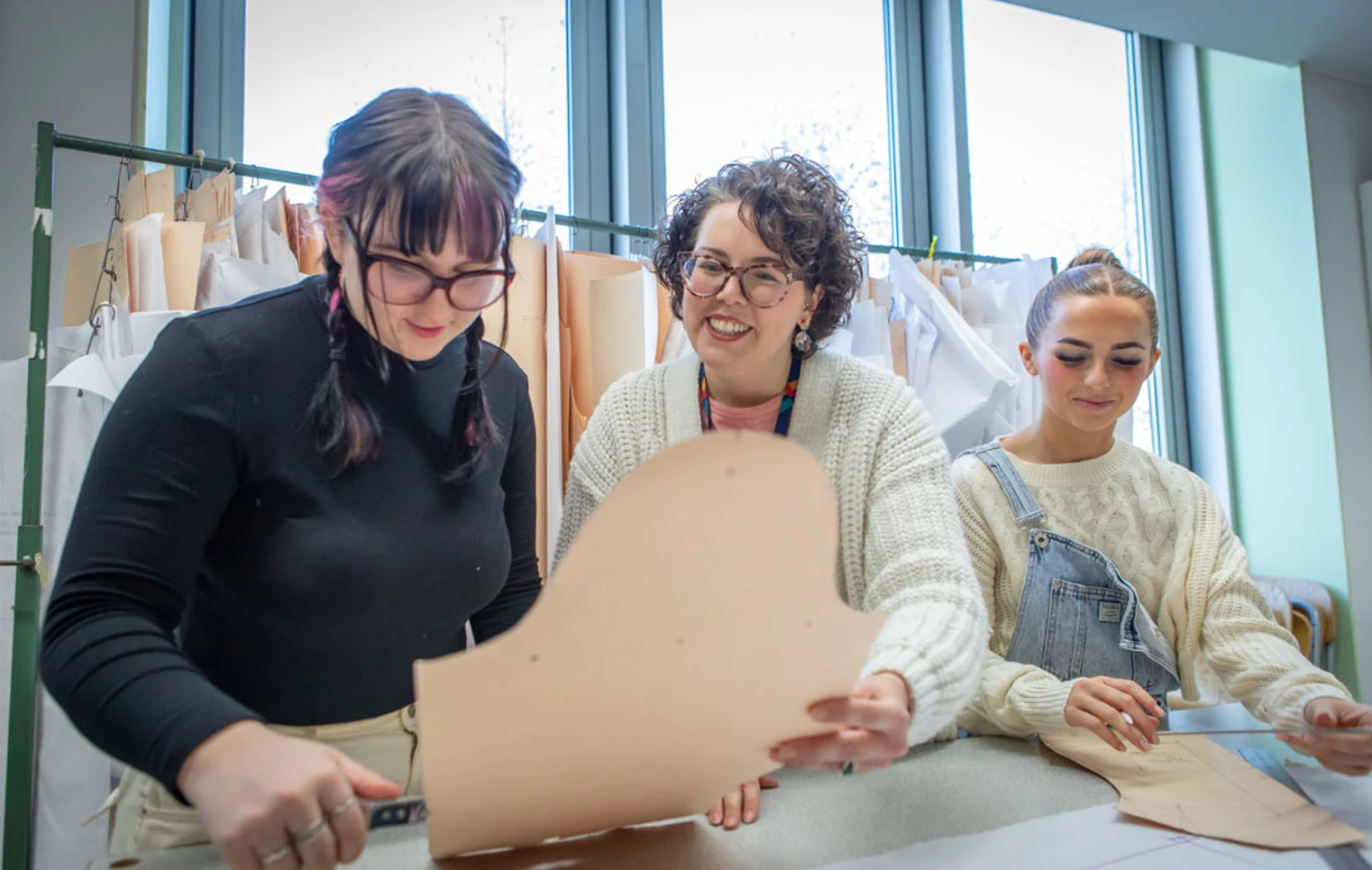 Fashion students collaborating on a sewing project under the guidance of their lecturer. Fashion students collaborating on a sewing project under the guidance of their lecturer.